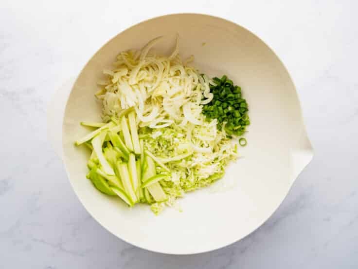 Vegetables and apple in a large bowl.