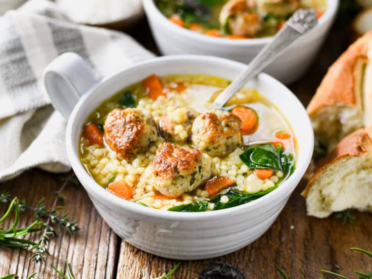 Horizontal side shot of a spoon in a bowl of Italian wedding soup.