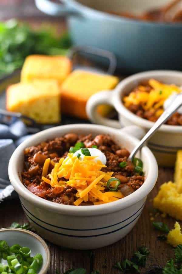 Front shot of two bowls of chili with cheese and other toppings