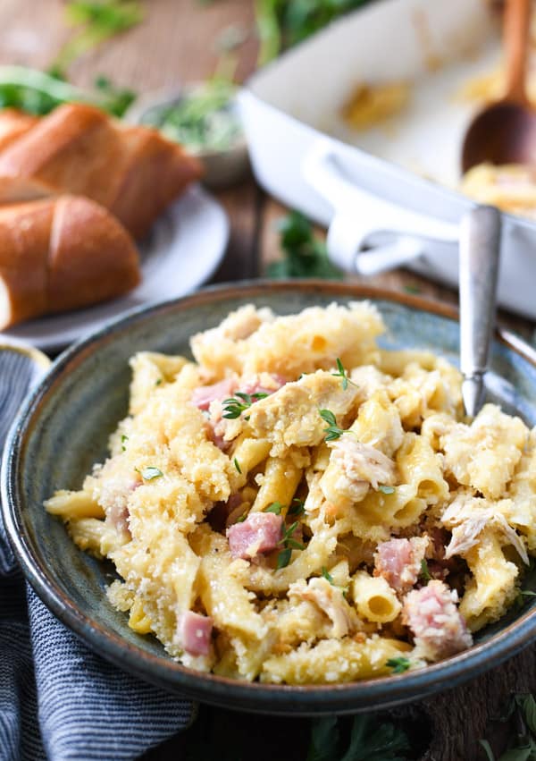A bowl full of chicken cordon bleu casserole made with penne pasta, chicken, and ham in a creamy sauce.