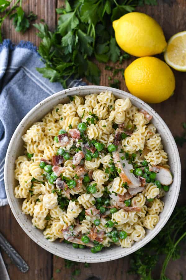 Overhead image of a bowl of creamy chicken pasta with bacon lemon and peas