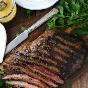 Overhead image of grilled flank steak with bourbon glaze on a wooden cutting board