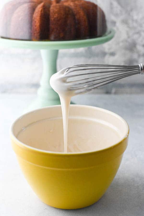 Lemon glaze for Bundt cake in a small yellow bowl with a whisk
