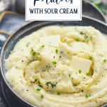 Close up side shot of creamy mashed potatoes with sour cream and chives with text title overlay