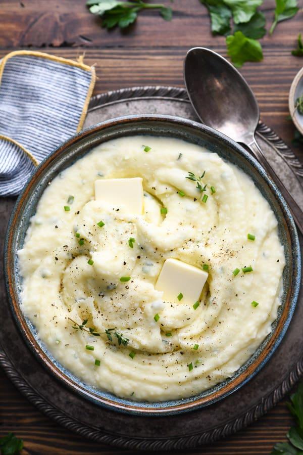 Overhead shot of creamy mashed potatoes with sour cream and chives on a wooden table