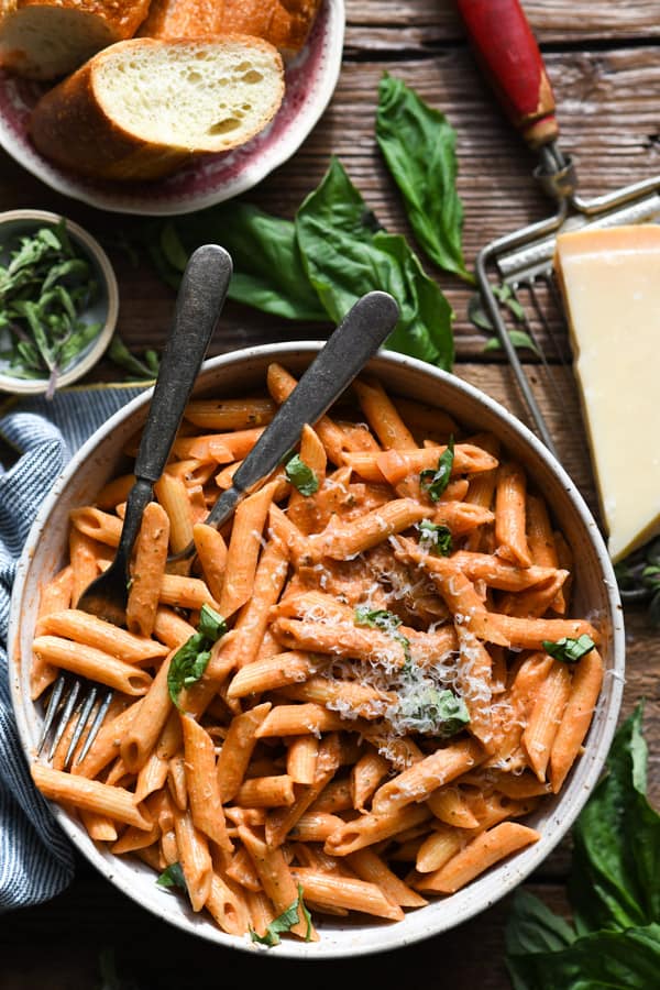 Easy penne alla vodka in a bowl with fresh basil and Parmesan garnish