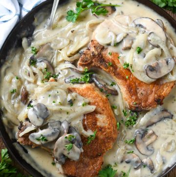 Close overhead shot of smothered pork chops with mushroom and onion gravy in a cast iron skillet