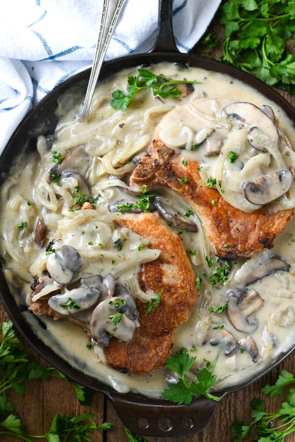 Close overhead shot of smothered pork chops with mushroom and onion gravy in a cast iron skillet
