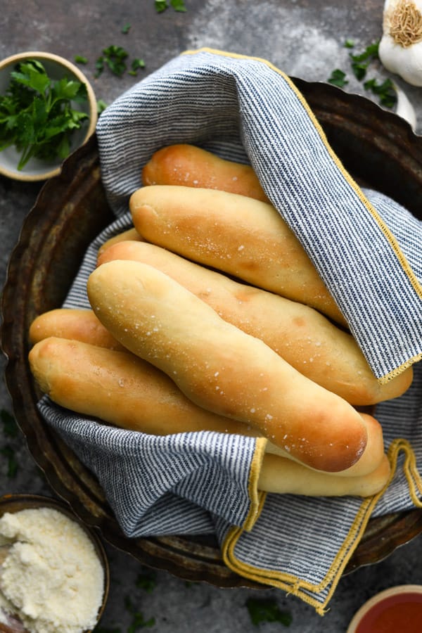 Overhead shot of a basket of homemade breadsticks wrapped in a blue towel