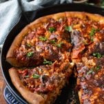 Close up side shot of a cast iron skillet pizza on a wooden board