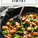 Side shot of a skillet of Chinese chicken broccoli stir fry with text title box at top
