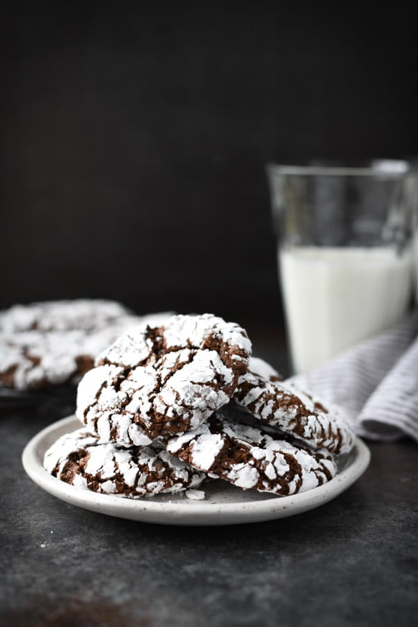 Plate of classic chocolate crinkle cookies with a glass of milk in the background