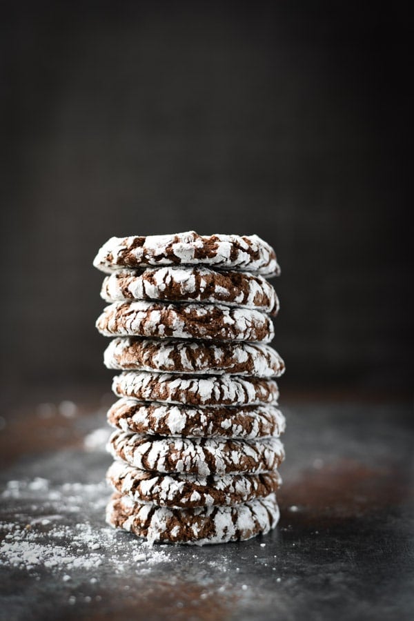 Tall stack of chocolate crinkle cookies in front of a dark wall