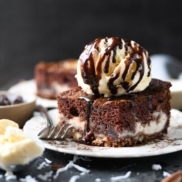 Square image of chocolate earthquake cake on a plate with a scoop of vanilla ice cream