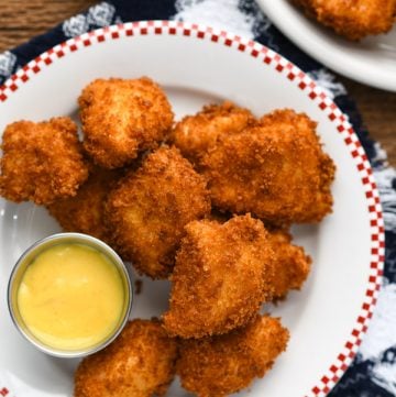 Close overhead shot of a plate of homemade chicken nuggets on a wooden table.