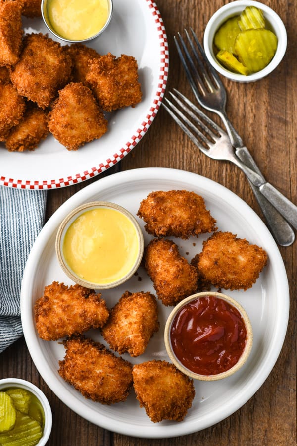 Overhead shot of homemade chicken nuggets on a white plate with dip