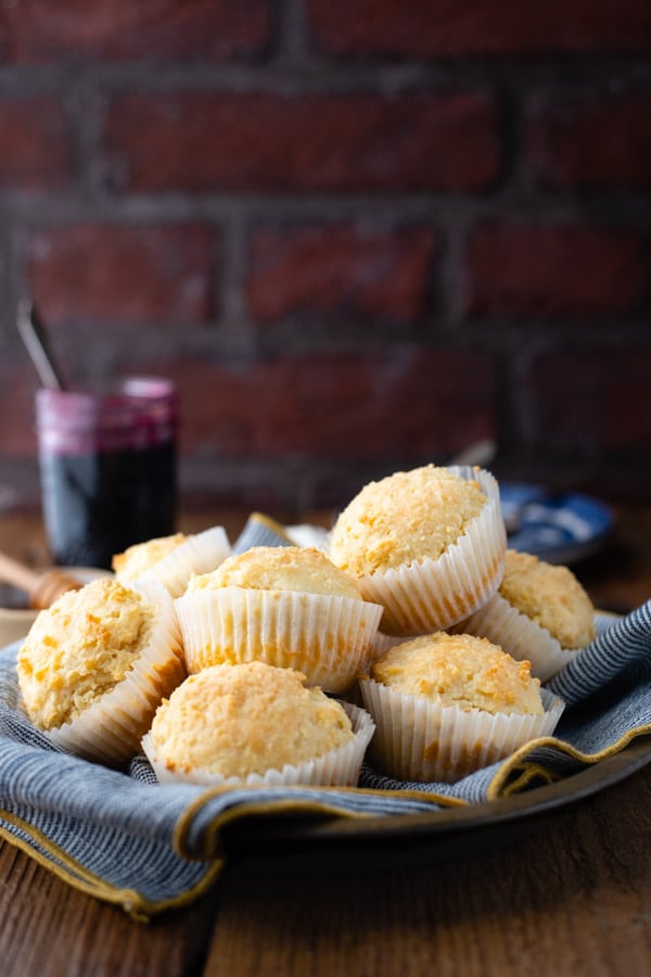 Basket of 3 ingredient sour cream muffins on a table in front of a brick wall