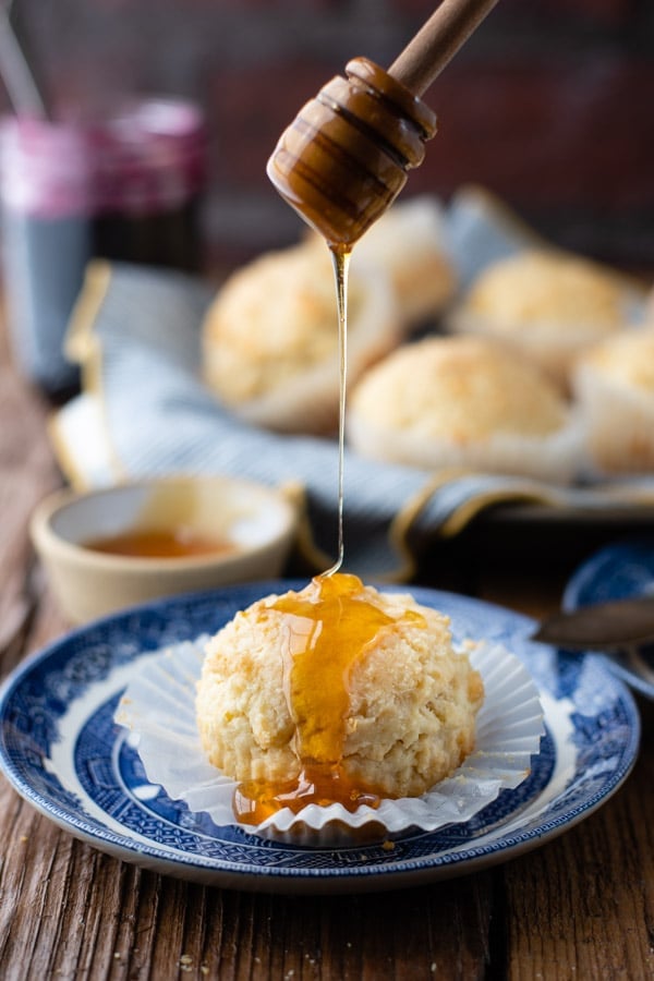 Drizzling honey over a sour cream muffin on a plate
