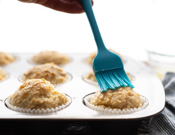 Brushing melted butter on sour cream muffins