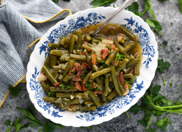 Overhead shot of a bowl of fresh green beans cooked country style and served in a blue and white dish
