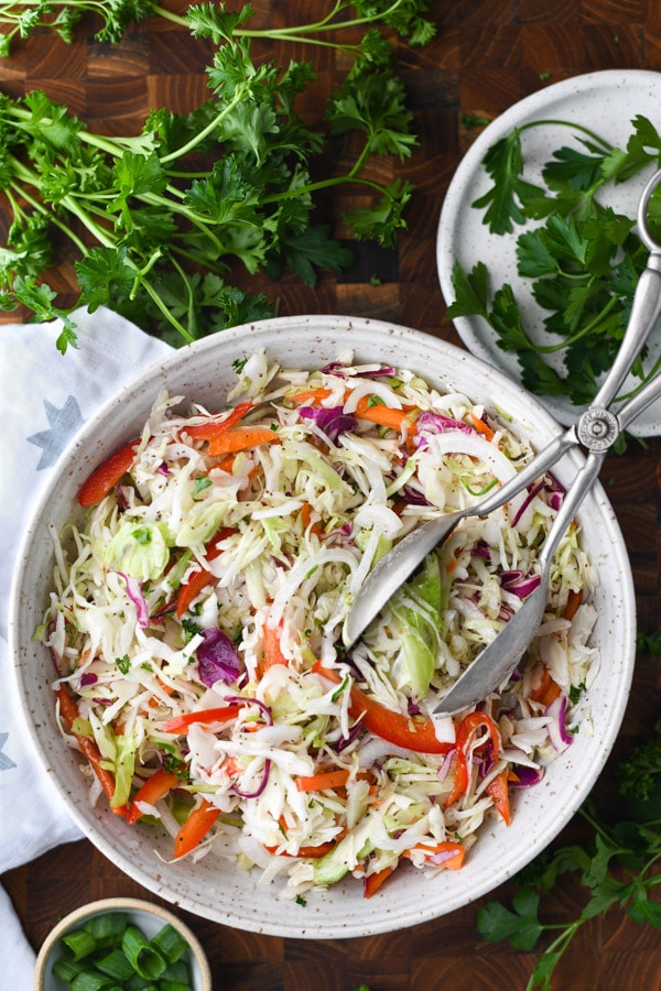 Overhead shot of a bowl of Southern vinegar slaw with serving tongs