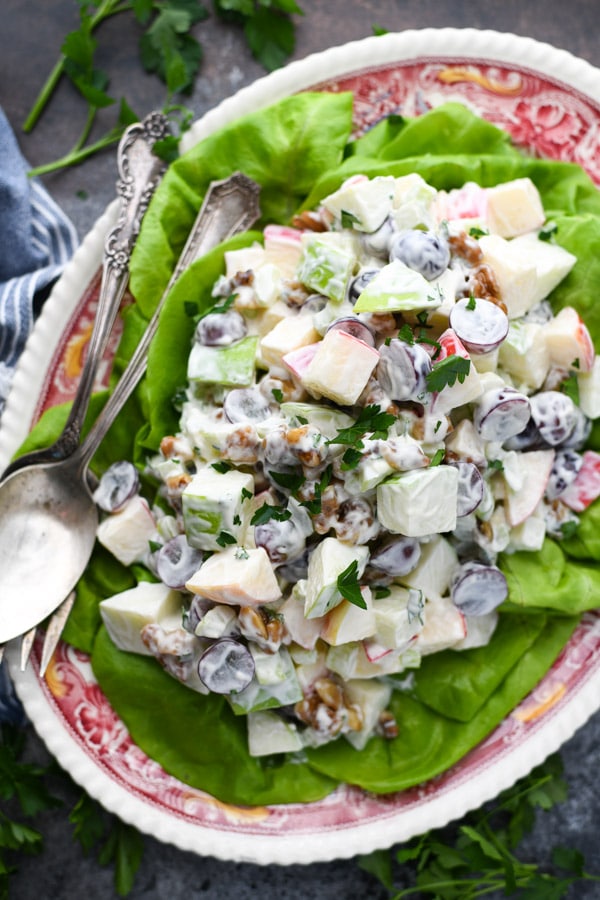 The best Waldorf Salad recipe served on a vintage red and white platter and a bed of lettuce.