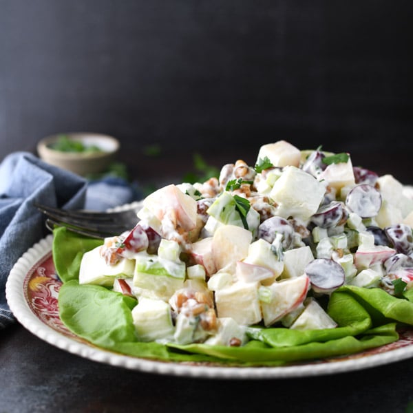 Square side shot of a plate full of a classic Waldorf Salad recipe served on a bed of lettuce.