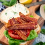 Layering the ultimate BLT sandwich on a cutting board
