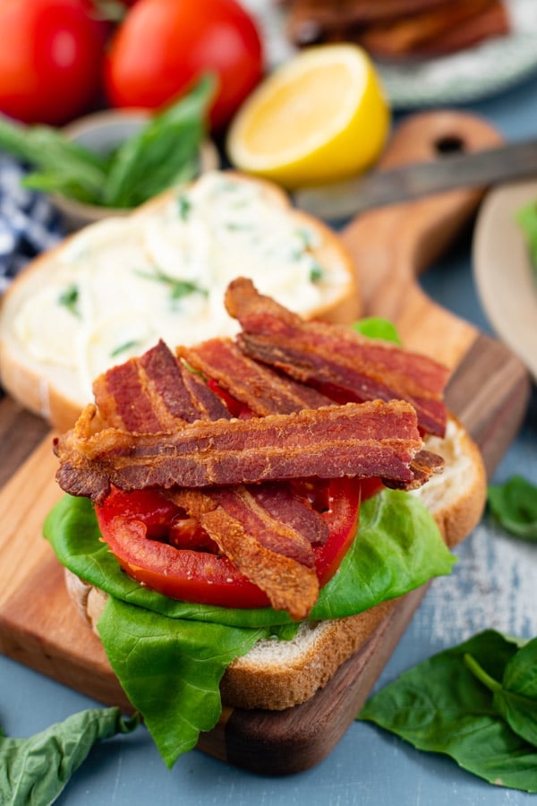 Layering the ultimate BLT sandwich on a cutting board