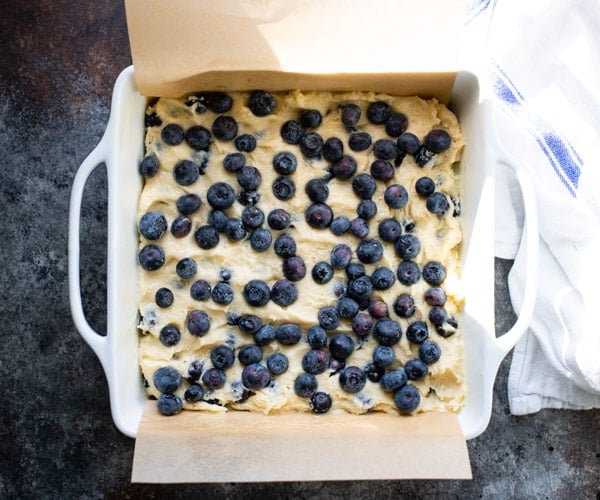 Adding blueberries to a moist blueberry buckle cake