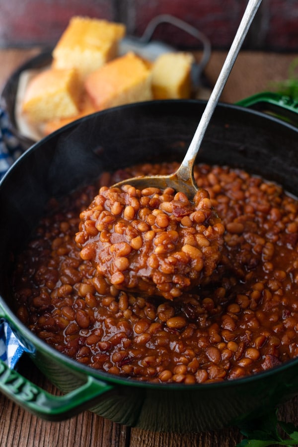Close up shot of a ladle of homemade baked beans with bacon and molasses