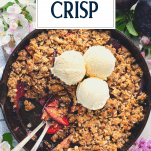Close overhead shot of plum crisp in a cast iron skillet with text title overlay