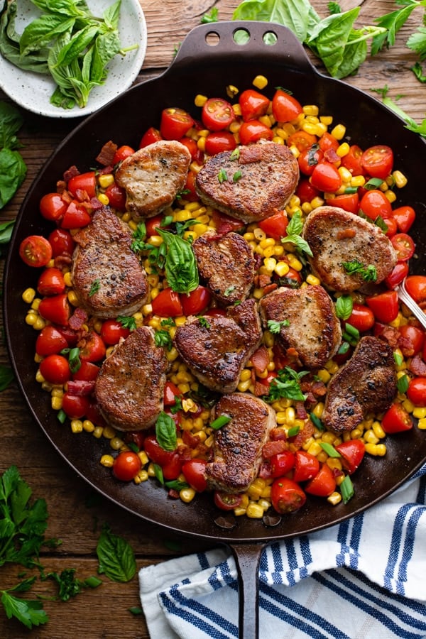 Overhead close up shot of a skillet full of pork medallions recipe with corn and bacon