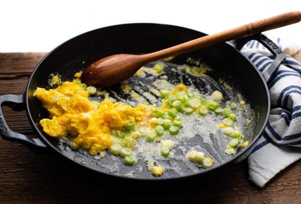Cooking eggs with green onions in a skillet