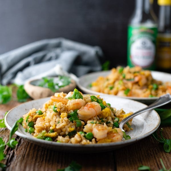 Square shot of a plate of easy shrimp fried rice on a plate in front of a dark background