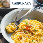 Close up shot of a bowl of creamy spaghetti carbonara with text title overlay