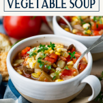 Side shot of summer vegetable soup in a white bowl with text title box at top