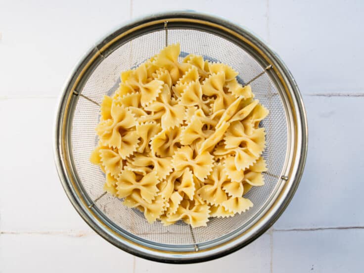 Cooked and drained bowtie pasta in a colander.
