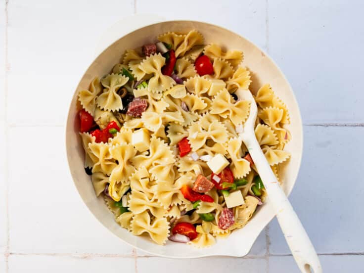 Combining the pasta, meats, and cheeses in a large bowl.