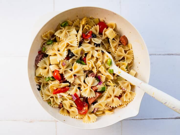 Tossing the red wine vinaigrette with the pasta salad ingredients.