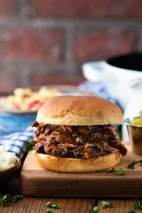 Front shot of a shredded beef bbq sandwich on a wooden cutting board