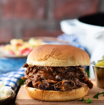 Front shot of a shredded beef bbq sandwich on a wooden cutting board