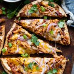 Close overhead shot of bbq chicken flatbread pizza sliced on a wooden cutting board