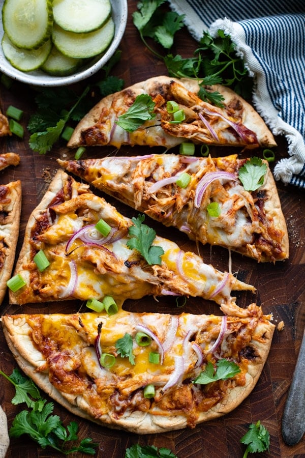 Close overhead shot of bbq chicken flatbread pizza sliced on a wooden cutting board