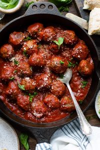 Close overhead image of a spoon in a skillet of oven baked meatballs with sauce