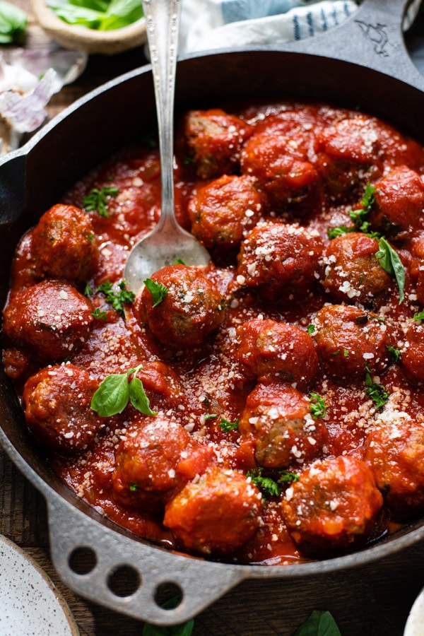 Close up front shot of a spoon in a pan of Italian baked meatballs