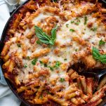 Close overhead image of a serving spoon in a dish of homemade baked ziti with sausage