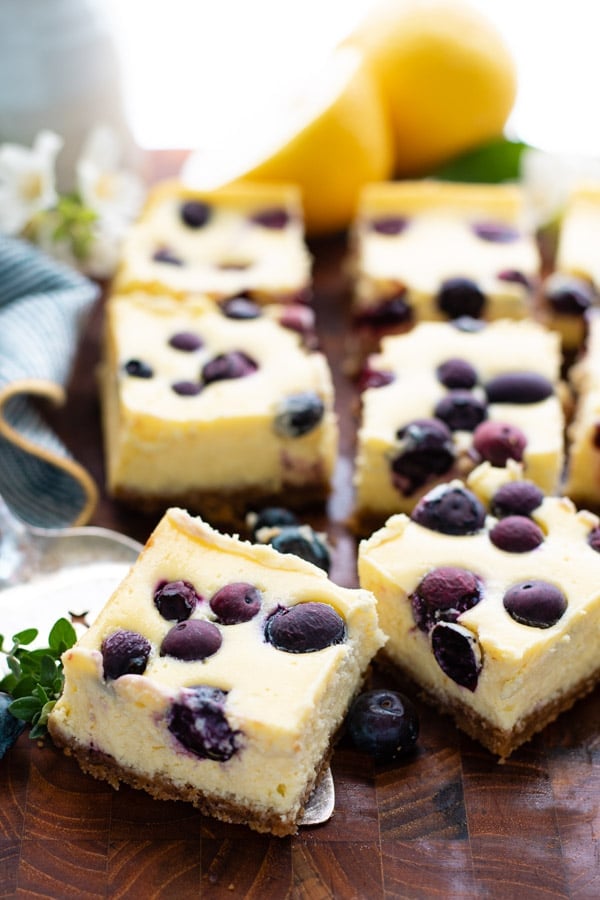 Close up side shot of lemon blueberry cheesecake bars on a cutting board
