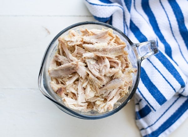 Shredded rotisserie chicken in a glass measuring cup