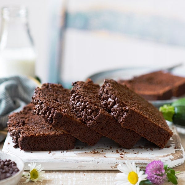Side shot of a loaf of moist chocolate zucchini bread sliced on a wooden board